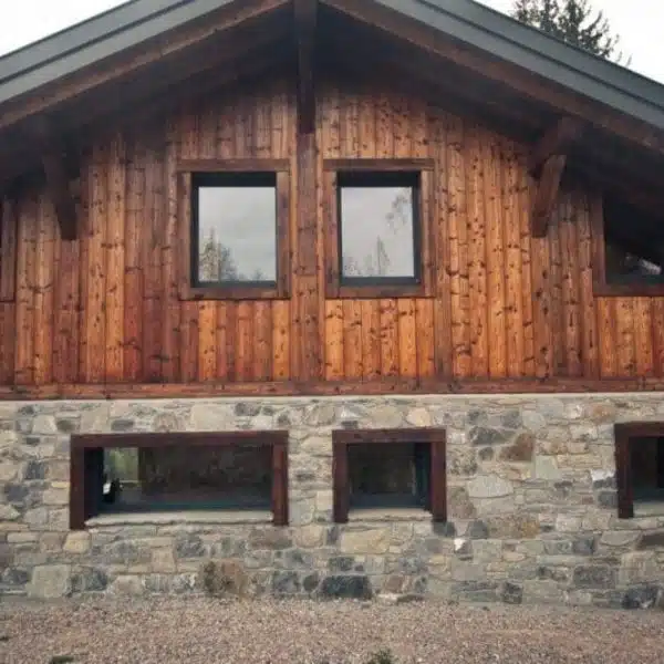 Protection du bois en extérieur avec la technique du yakisugi. chalet de montagne avec bardage bois brûlé brossé et soubassement en pierre