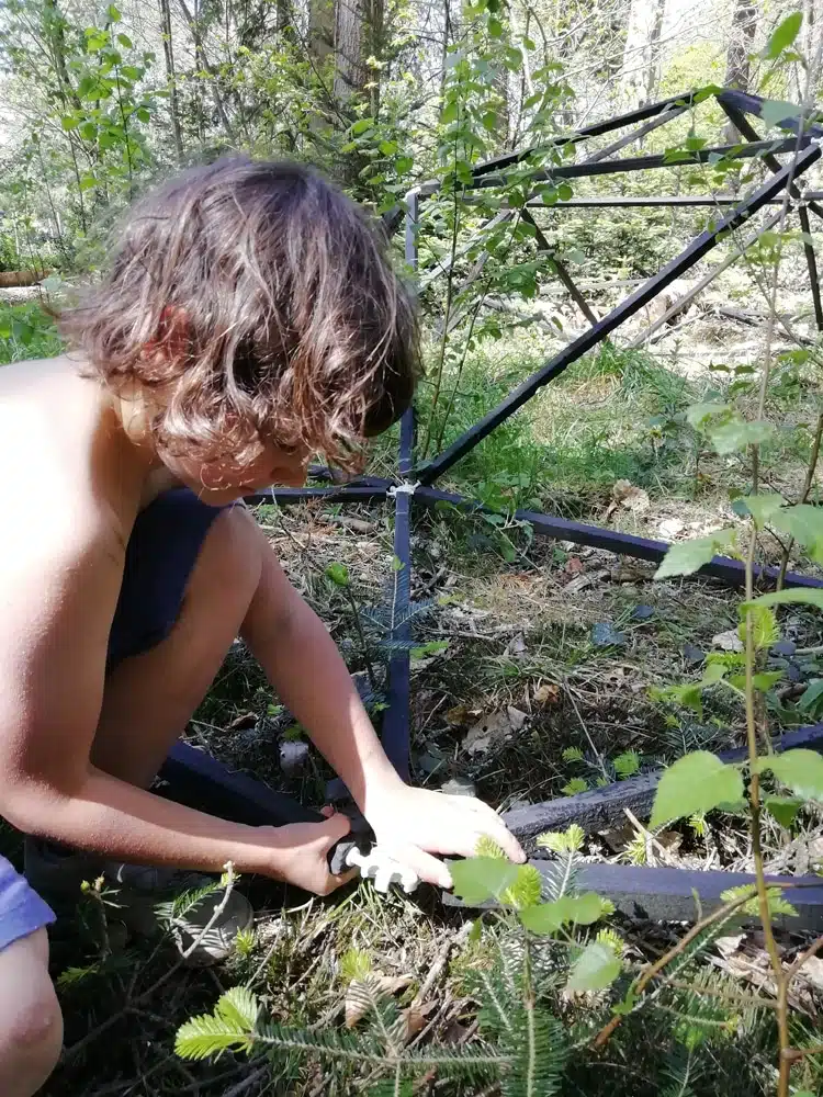 enfant qui assemble les pièces du kit de dôme géodésique